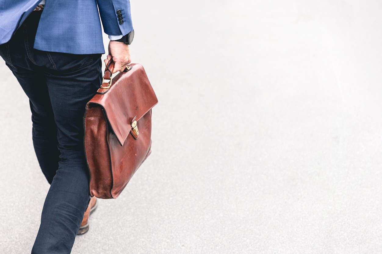 Close up of trousered individual walking holding a briefcase