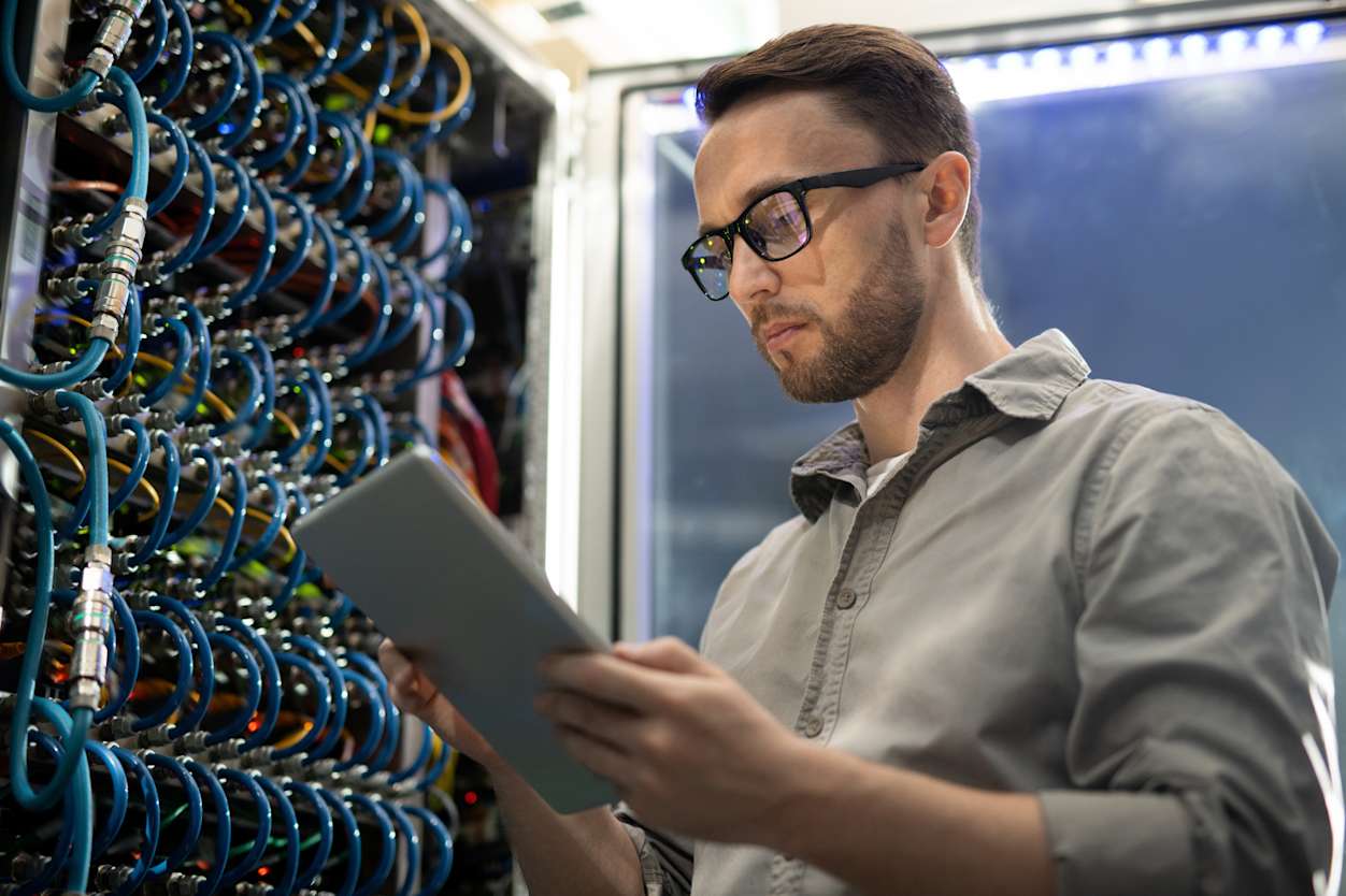 Man holds clipboard looking at server.
