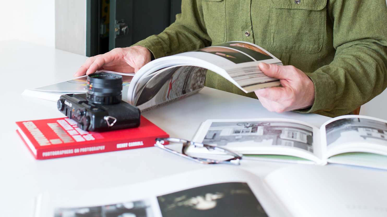 Man sitting at table looking through different polaroid images. @Matt Jessop