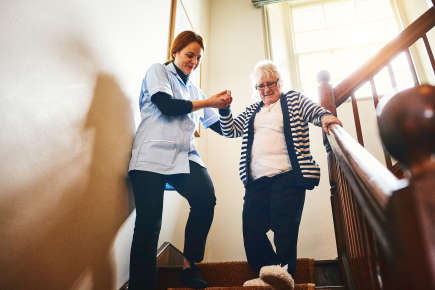 Nurse helping elderly patient down stairs