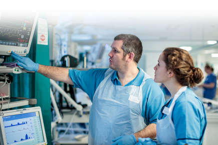 Two doctors, a man and woman, looking at a hospital machine.