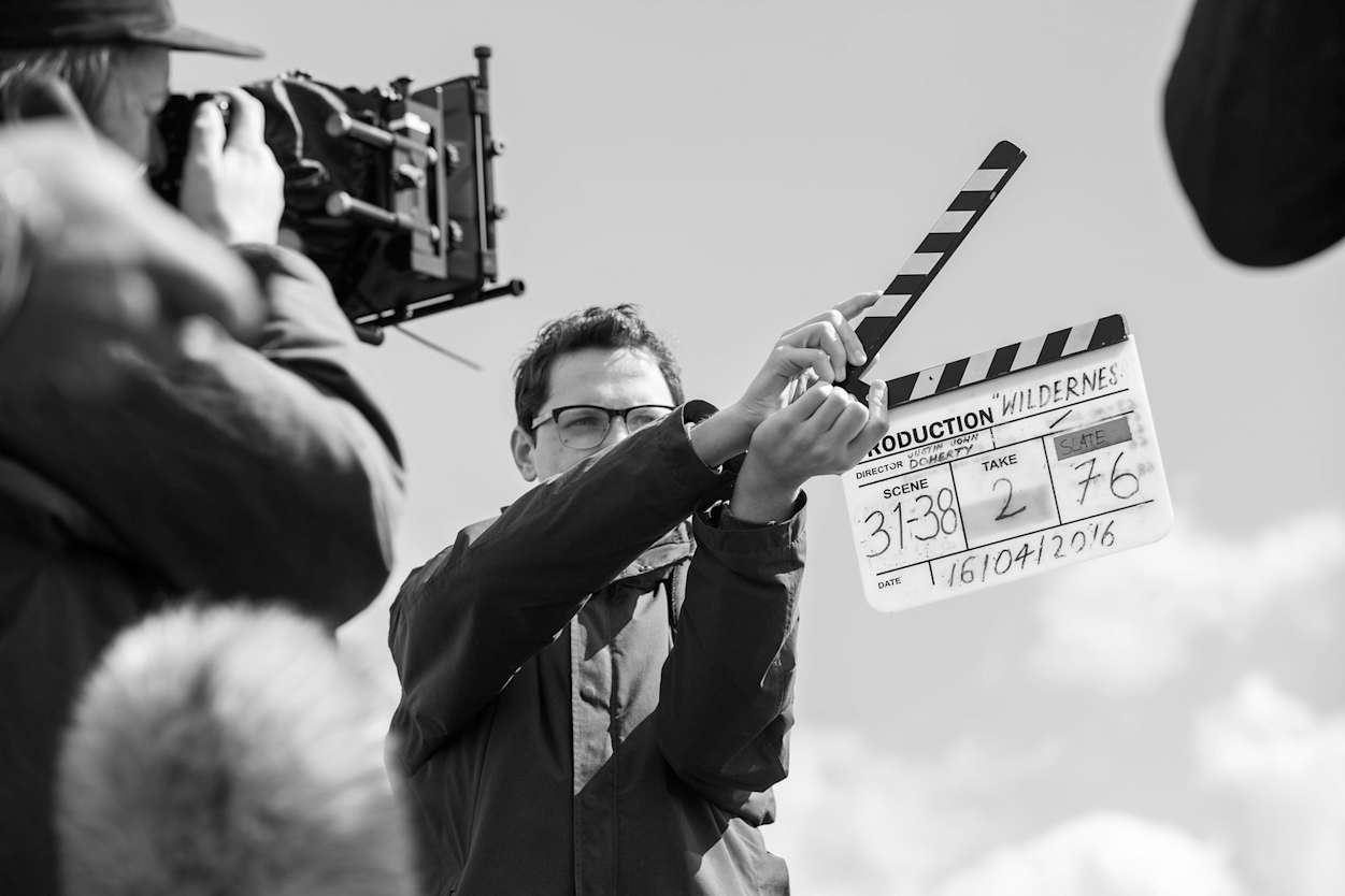 Black and white image of a man holding a clapperboard.