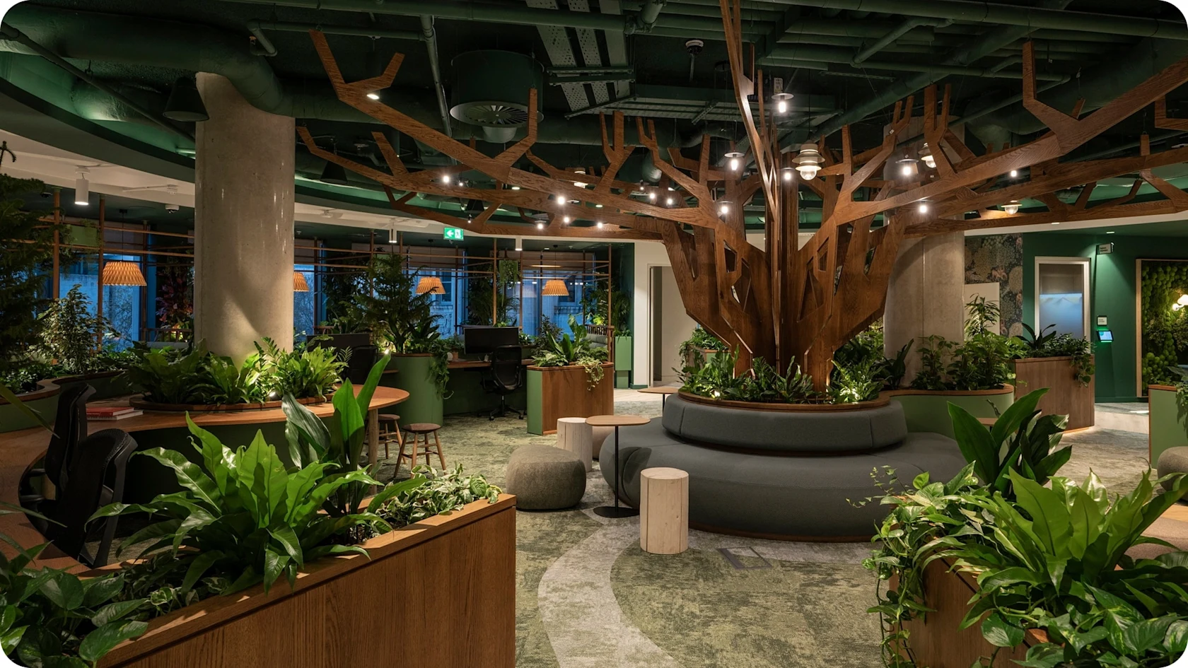 An office space with a lot of plants and a large wooden tree sculpture.
