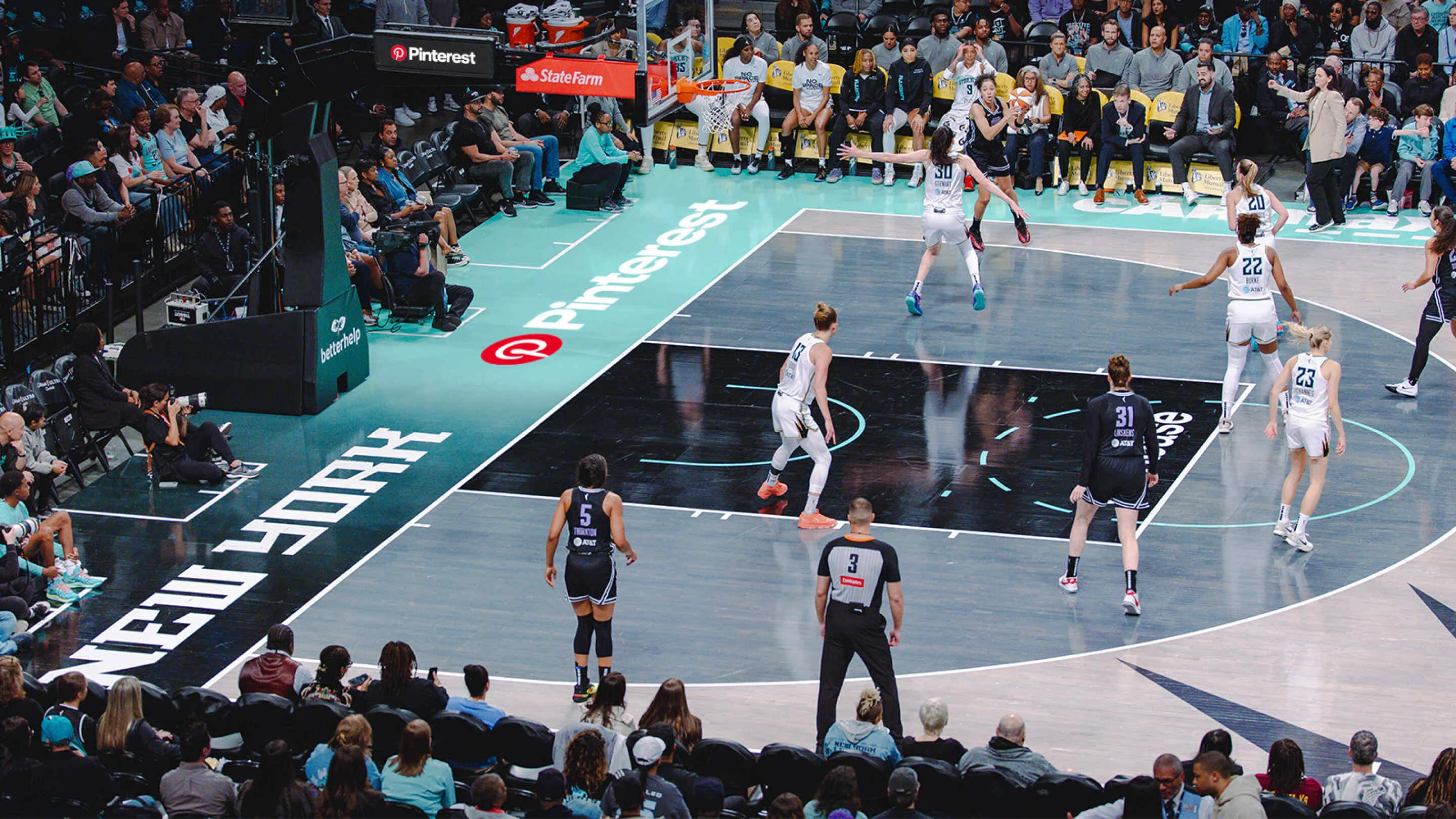 The New York Liberty WNBA team plays basketball on their home court. The Pinterest logo is painted on the sideline.