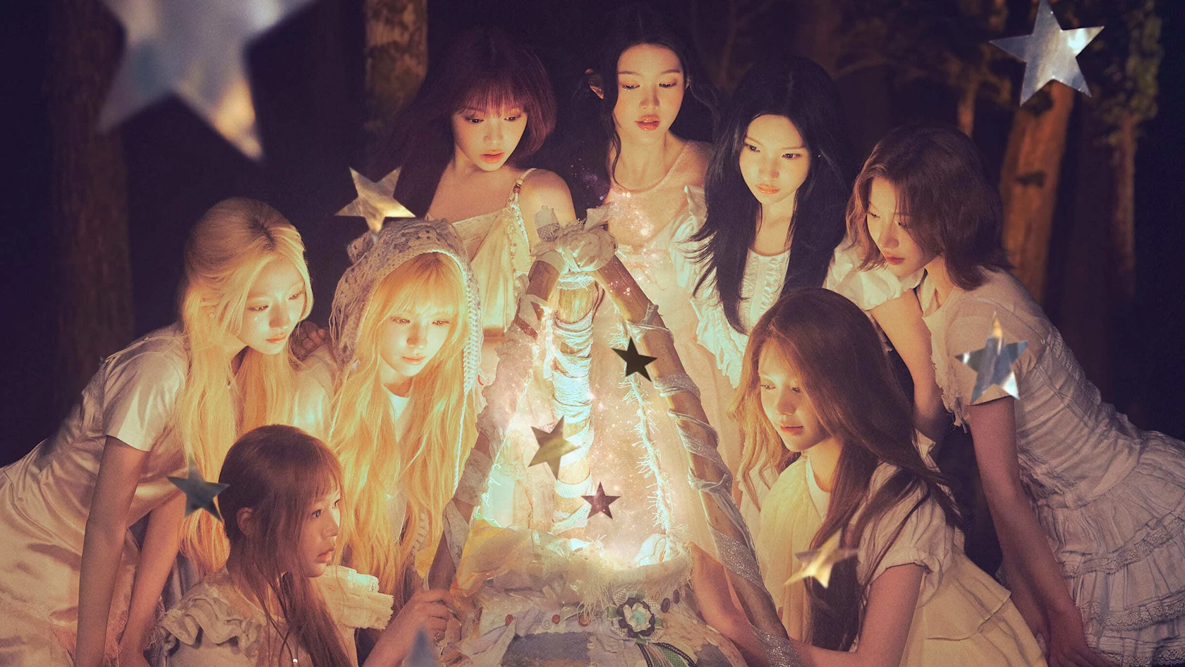 KPOPグループ Hearts2Hearts のメンバー8人が森の中で星の飾りがついた小さなテントを覗き込んでいる
