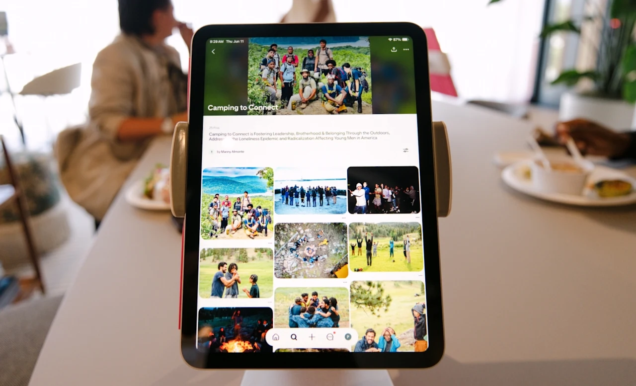 Tablet on a cafe table displaying a Pinterest board titled “Camping to Connect,” with blurred people eating at the table in the background.