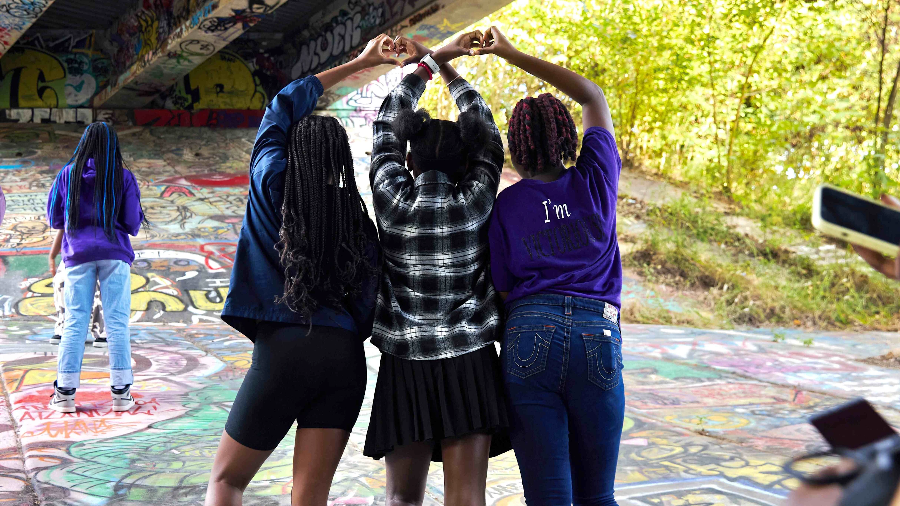 Teens with their back to camera using hands to make a heart shape