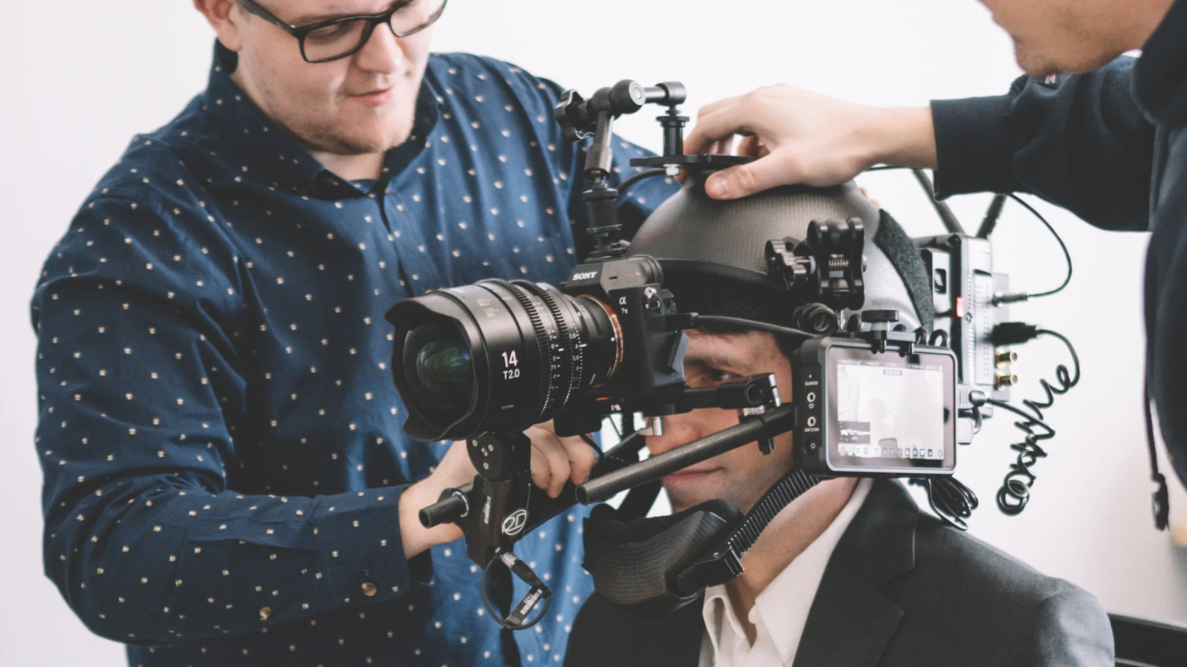 Crew member adjusts cables on a POV helmet camera rig strapped to an actor during a Sunlife video shoot.