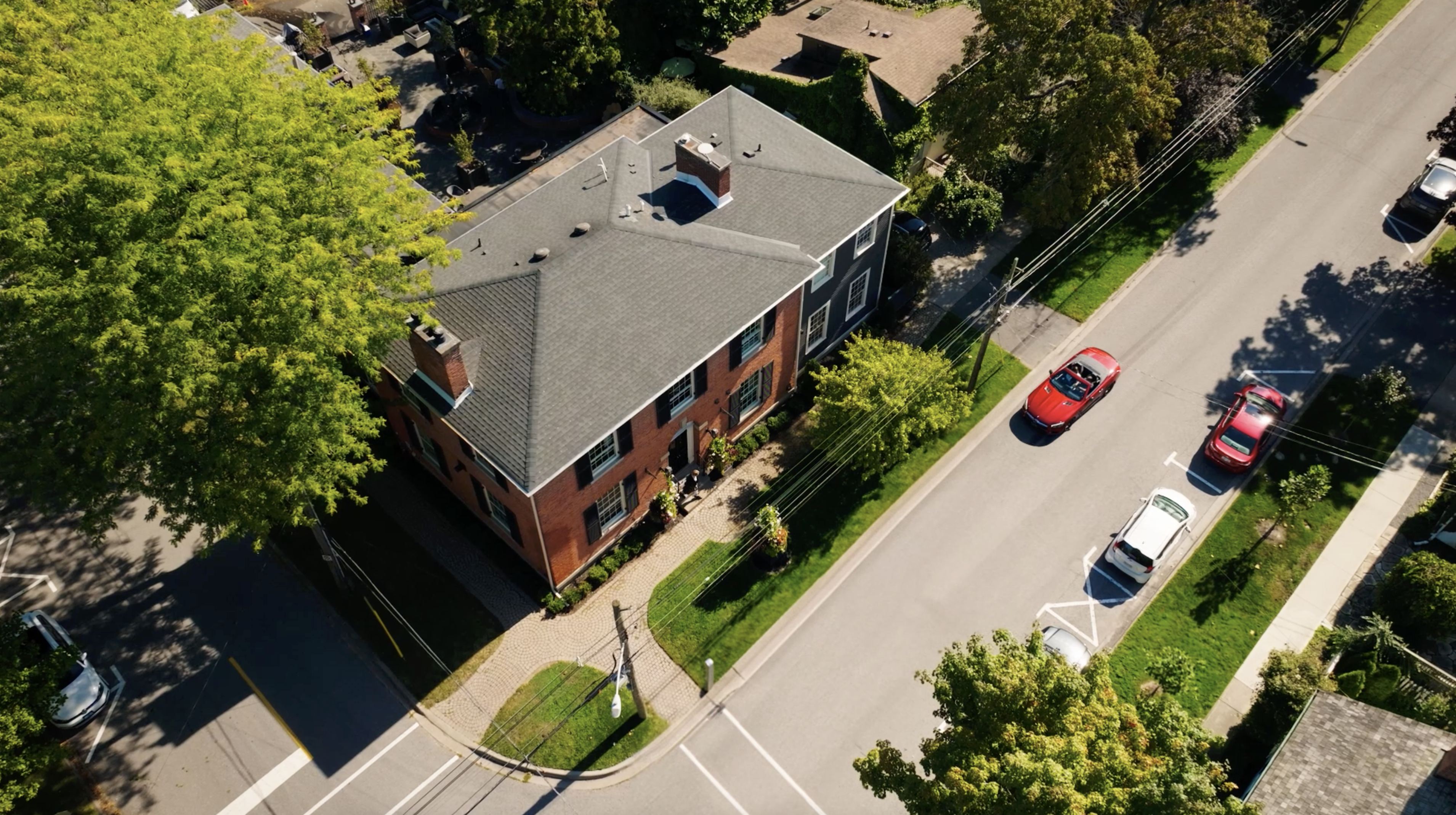 Drone shot from above of a couple arriving at The Scotsman Hotel in a red convertible in Niagara-on-the-Lake.