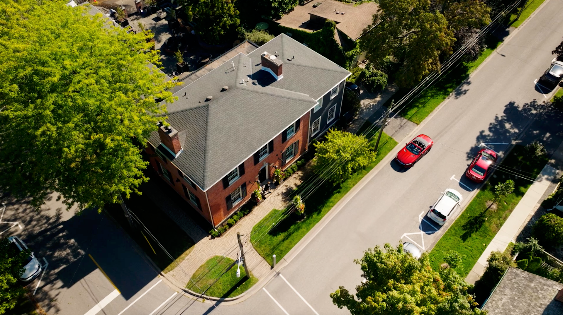 Drone shot from above of a couple arriving at The Scotsman Hotel in a red convertible in Niagara-on-the-Lake.