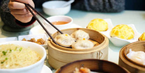 Person eating Chinese dim sum and dumplings with chopsticks at Cantonese restaurant in London 