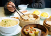 Person eating Chinese dumplings and dim sum with chopsticks at Cantonese restaurant in London