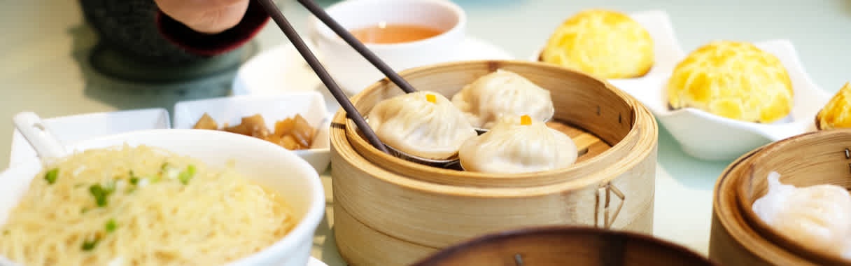 Person eating Chinese dim sum and dumplings with chopsticks at Cantonese restaurant in London