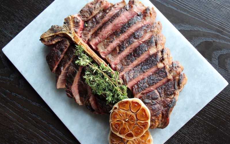 Photo of Stanbroke Black Angus Porterhouse at SKAI sliced with thyme on top 