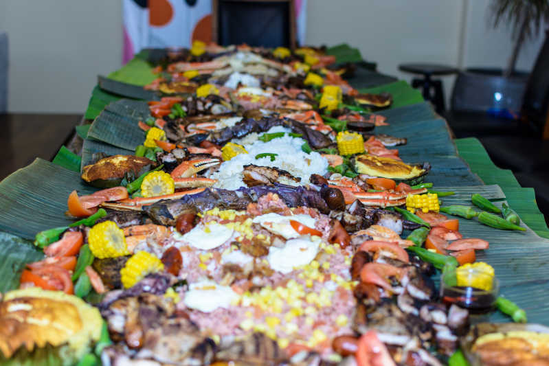 A proper Filipino feast laid out on a banana leaf with seasonal veggies, rice, plantain, veggie spring rolls, grilled corn and a gorgeous Filipino salad