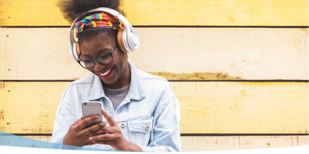 Chica con auriculares delante de una pared amarilla pálida