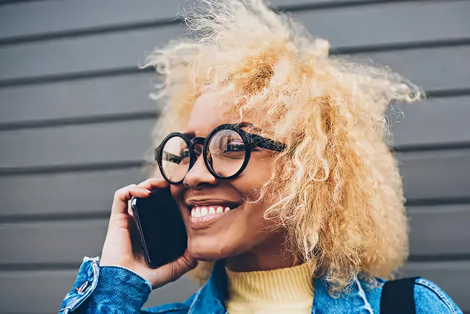 Mujer joven sonriente con gafas hablando por teléfono