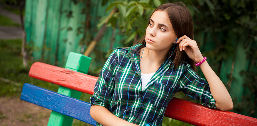 Una mujer pensativa con una camisa a cuadros sentada en un banco