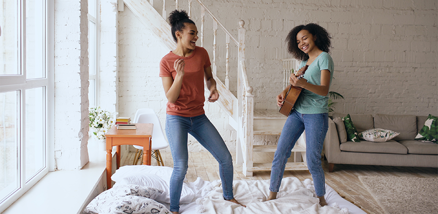 Dos mujeres en el salón: una bailando y la otra tocando la guitarra