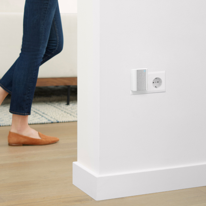 Ring Chime plugged into hallway socket with person walking past on wood floor near rug and sofa.