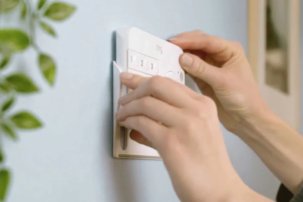 Hands attaching a Ring Alarm Keypad (1st Gen) to a wall bracket for secure, flexible home installation and monitoring.