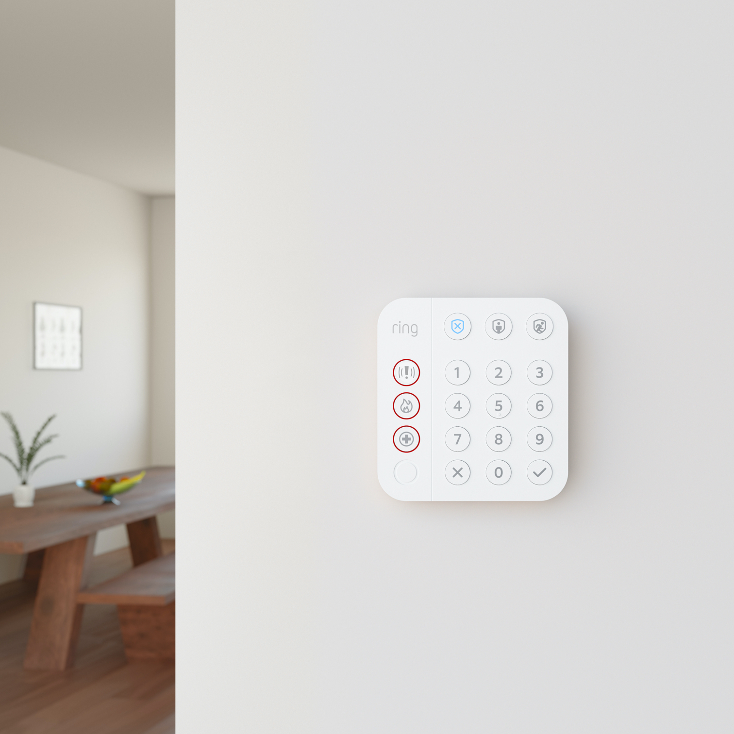 Ring Alarm Keypad mounted on a white interior wall, with a dining area visible in the background.