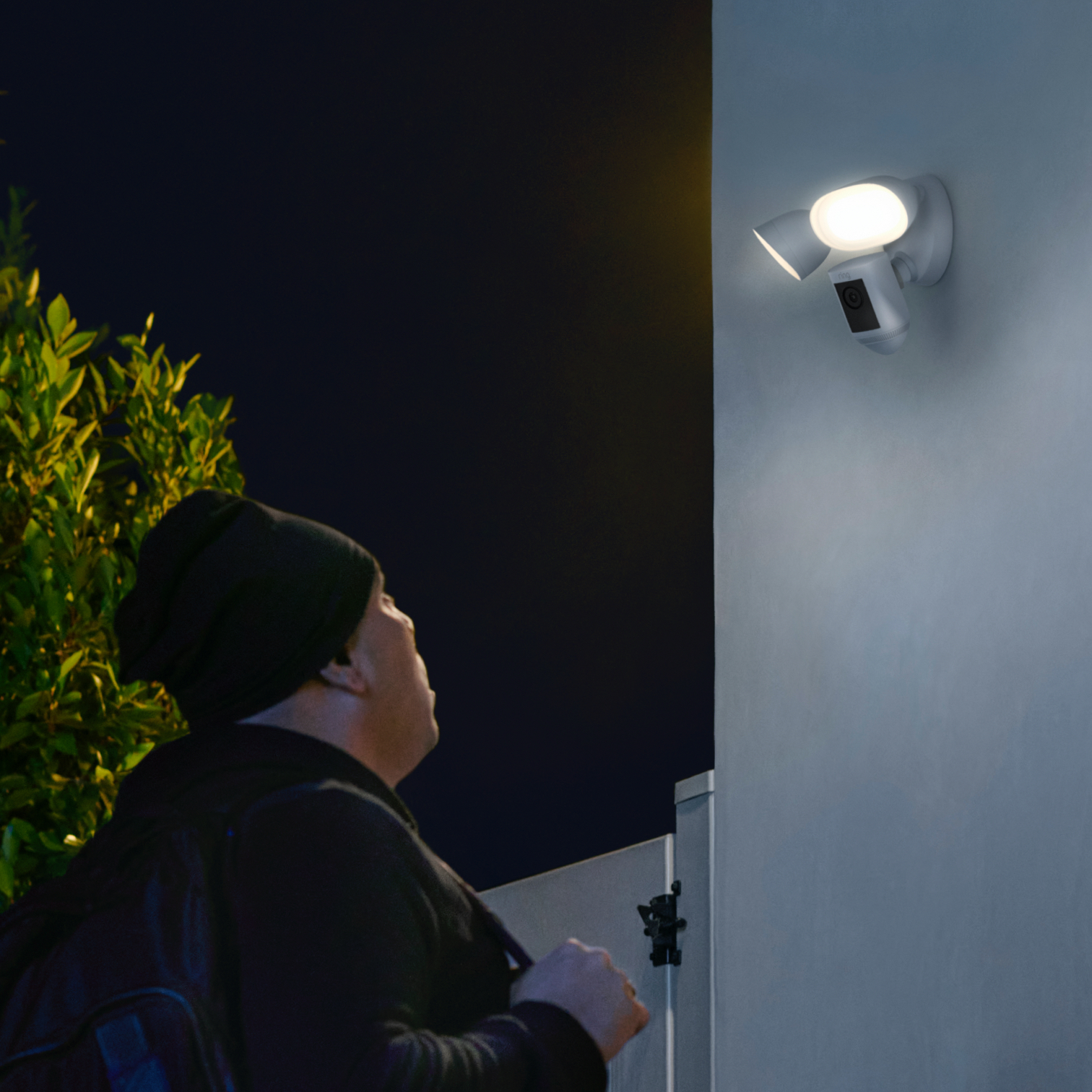 Floodlight Cam Wired Pro illuminates a person at night, capturing motion with 2K video and spotlight activation.