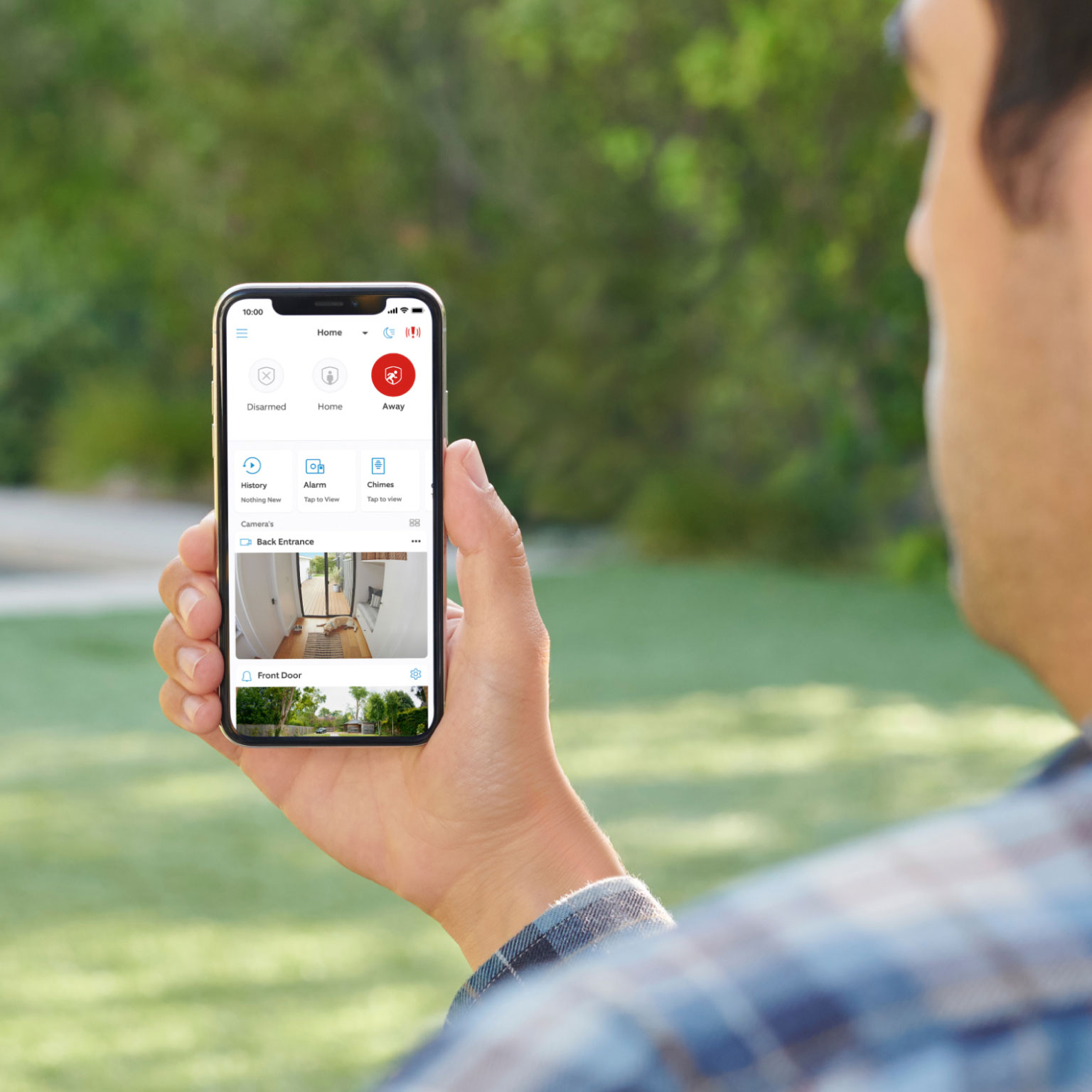 Person holding phone showing Ring app interface with live camera views and alarm system controls.