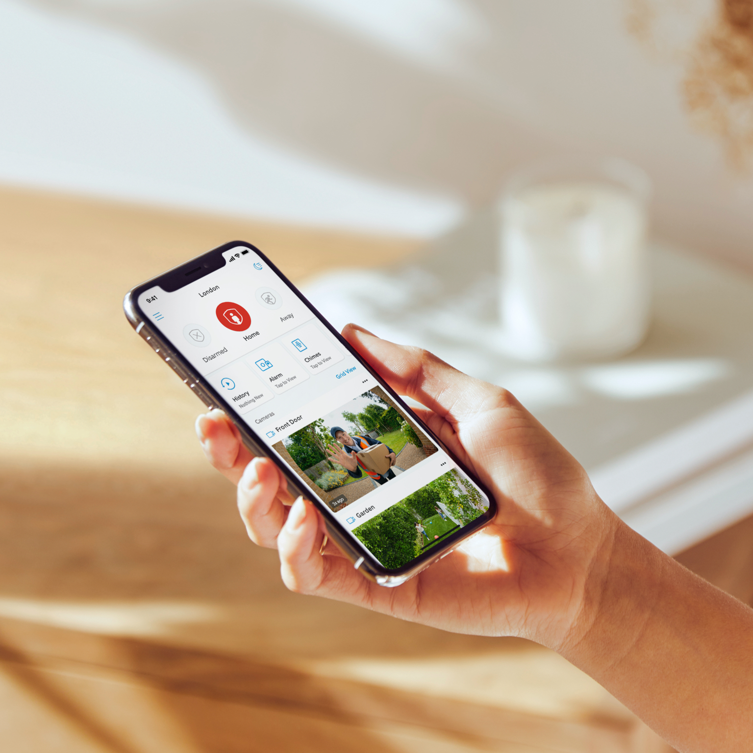 Hand holding smartphone displaying Ring app interface with live camera feed, privacy settings, and security controls.