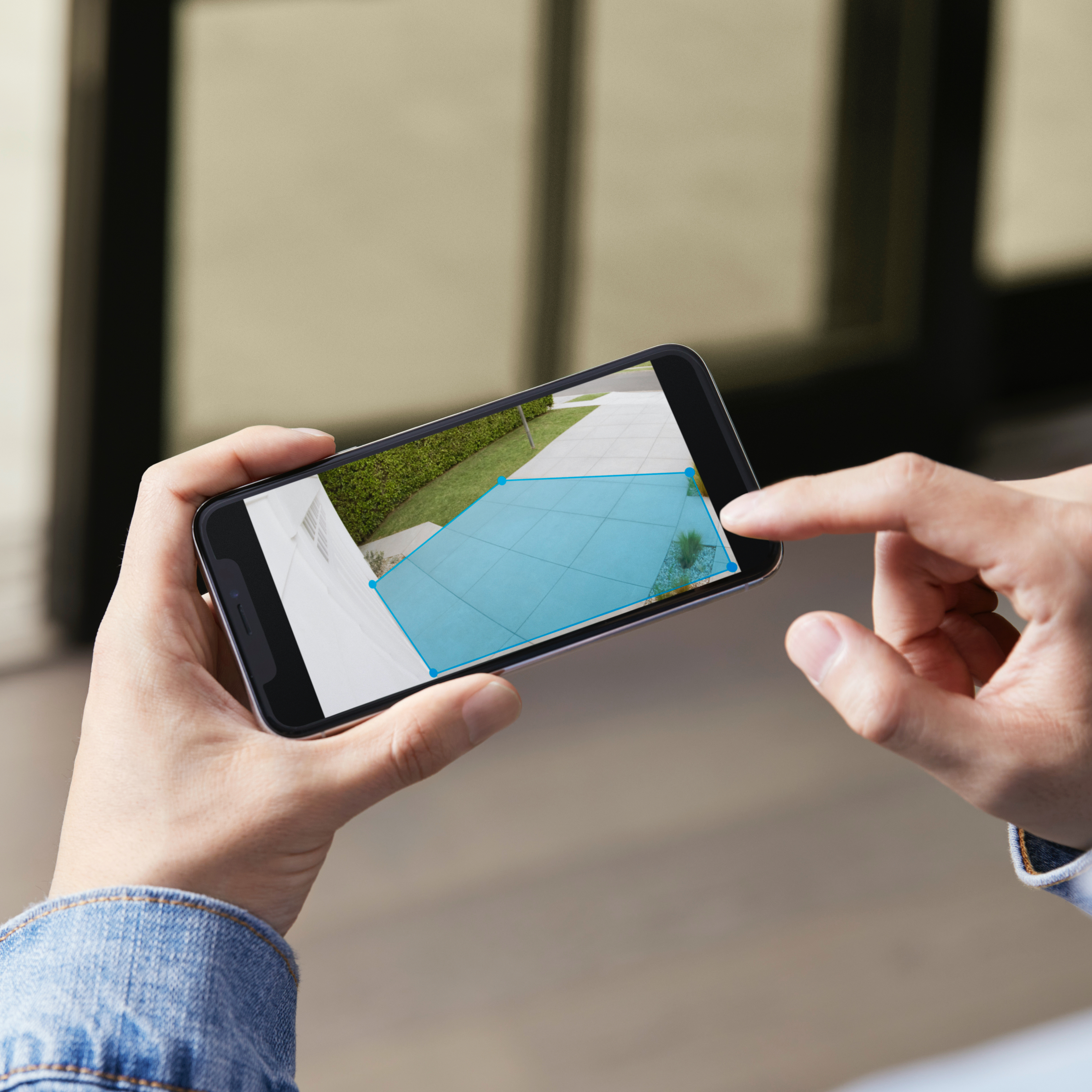 Person customises Motion Zones in the Ring app by adjusting a blue detection area on the live camera view.