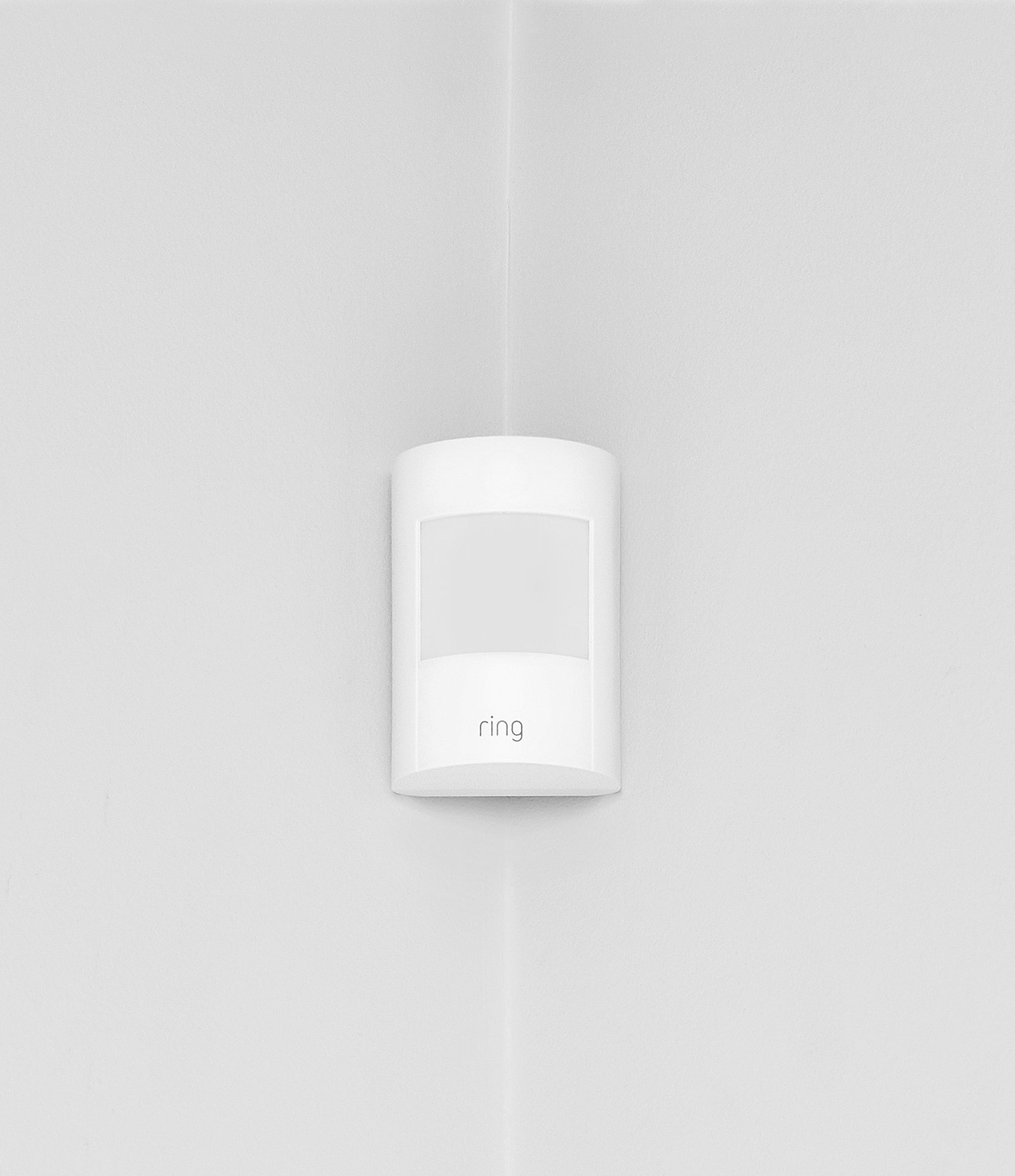 Ring Alarm Motion Detector mounted in room corner on a light grey indoor wall.