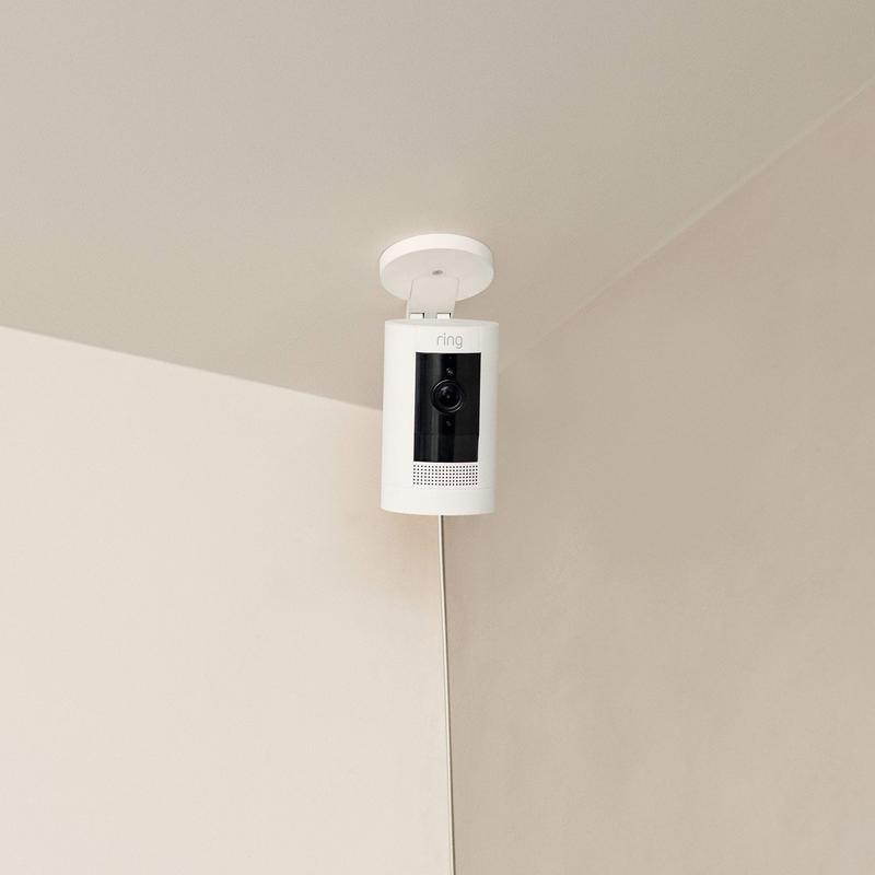 White Ring Stick Up Cam mounted upside down on ceiling with power cable running down the wall corner.