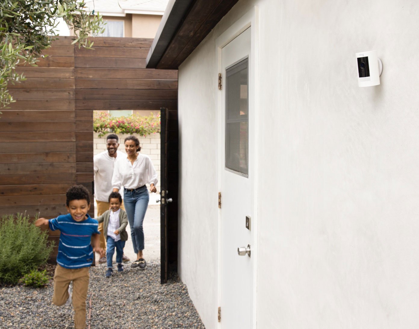 Family walking through gate while Ring Stick Up Camera Battery monitors home's outdoor area.