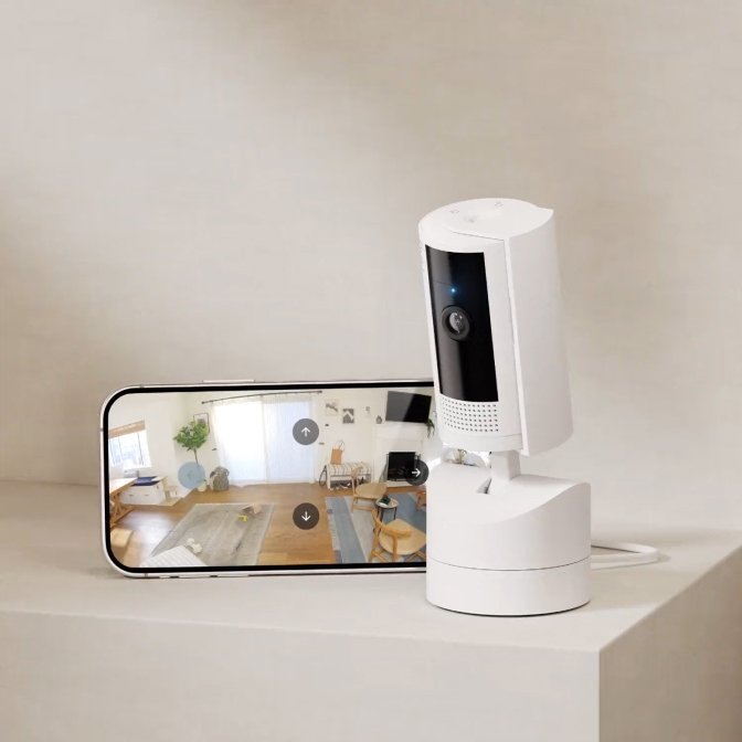 Ring Pan-Tilt Indoor Camera rotates while phone screen shows 360-degree room view using Ring app directional controls.