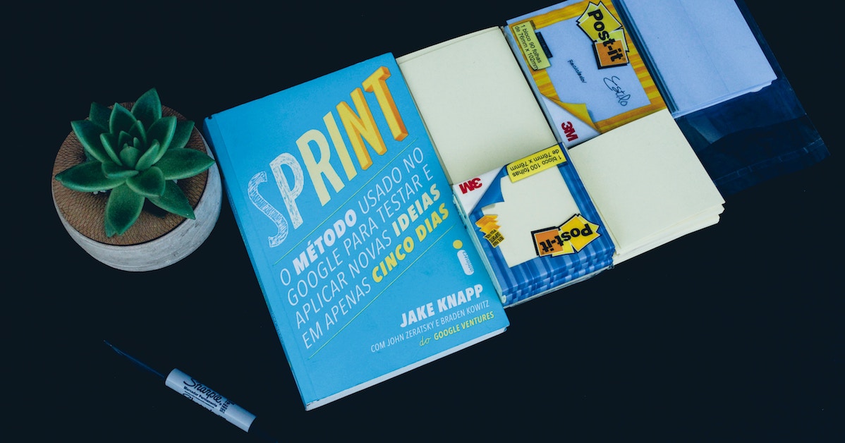 Livro Design Sprint na mesa ao lado de post its e uma caneta
