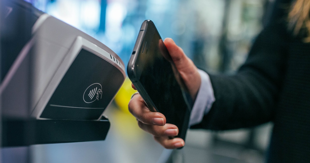 Pessoa passando celular para pagar algo com pagamento digital