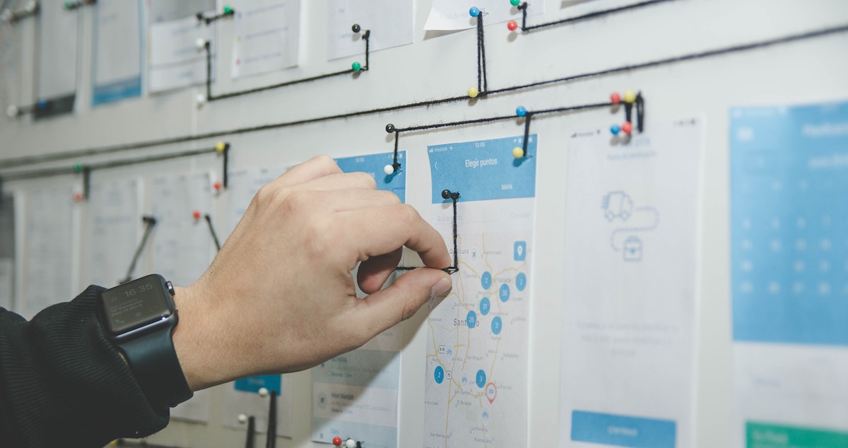 Mão fazendo testes em interface de usuário impressa que imita tela de aplicativo