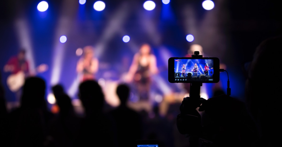 Pessoa gravando show com celular, um exemplo de possível live streaming