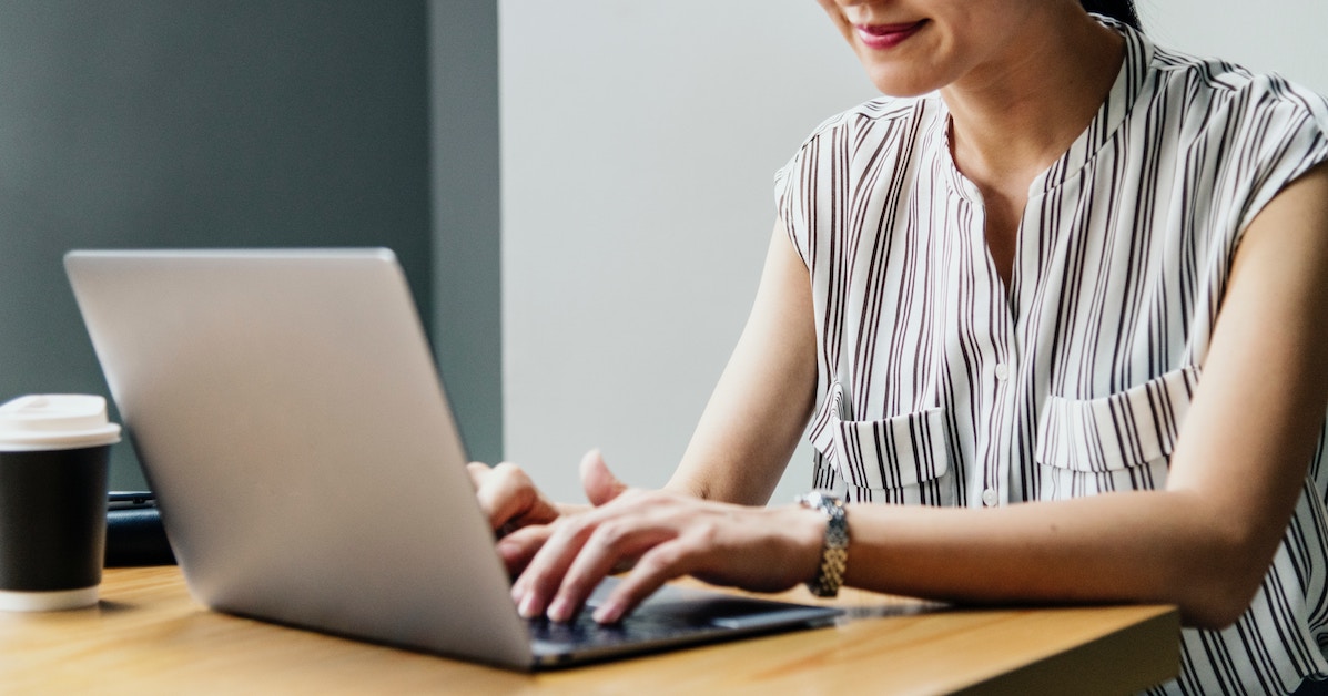 Mulher jovem digitando em laptop (foco nas mãos)