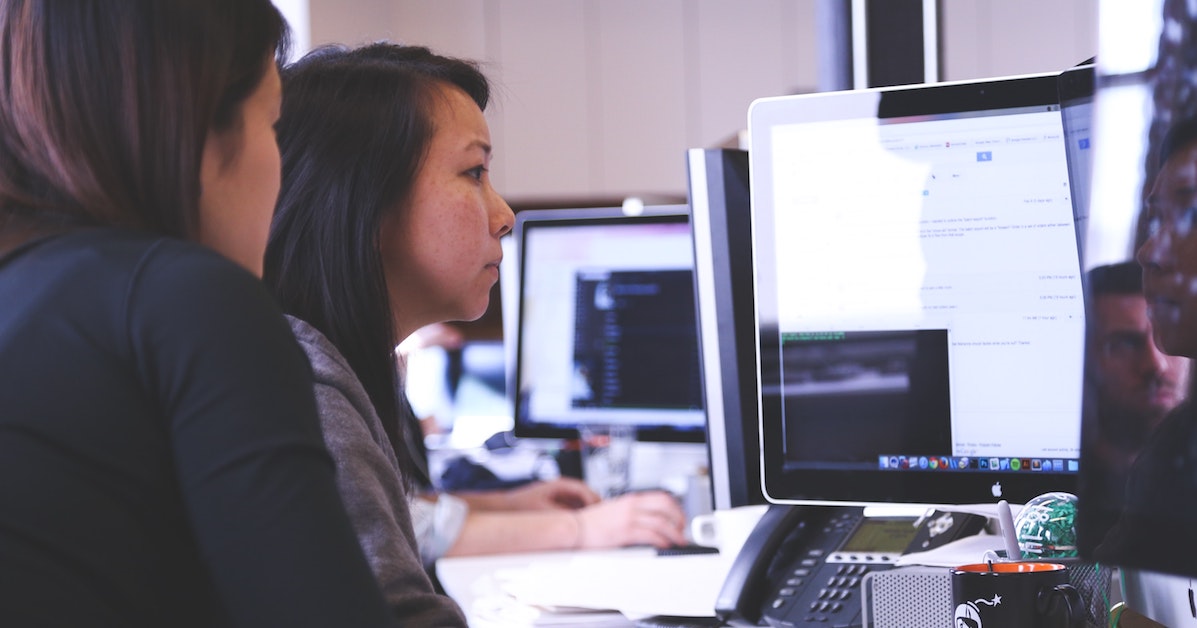 Dupla de programadoras trabalhando em computadores