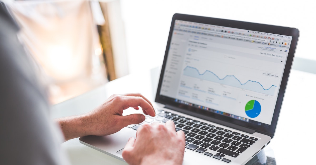Mãos digitando em laptop que está com a tela aberta no Google Analytics, uma das ferramentas de um analista de SEM