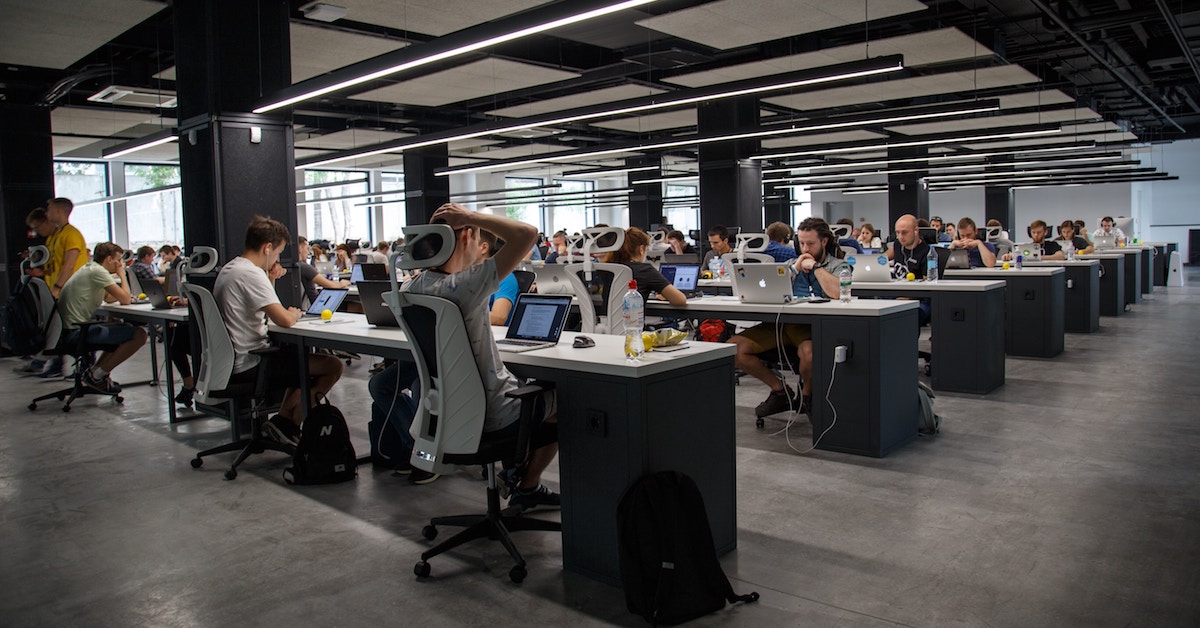 Pessoas trabalhando em frente a computadores em um escritório amplo e informal