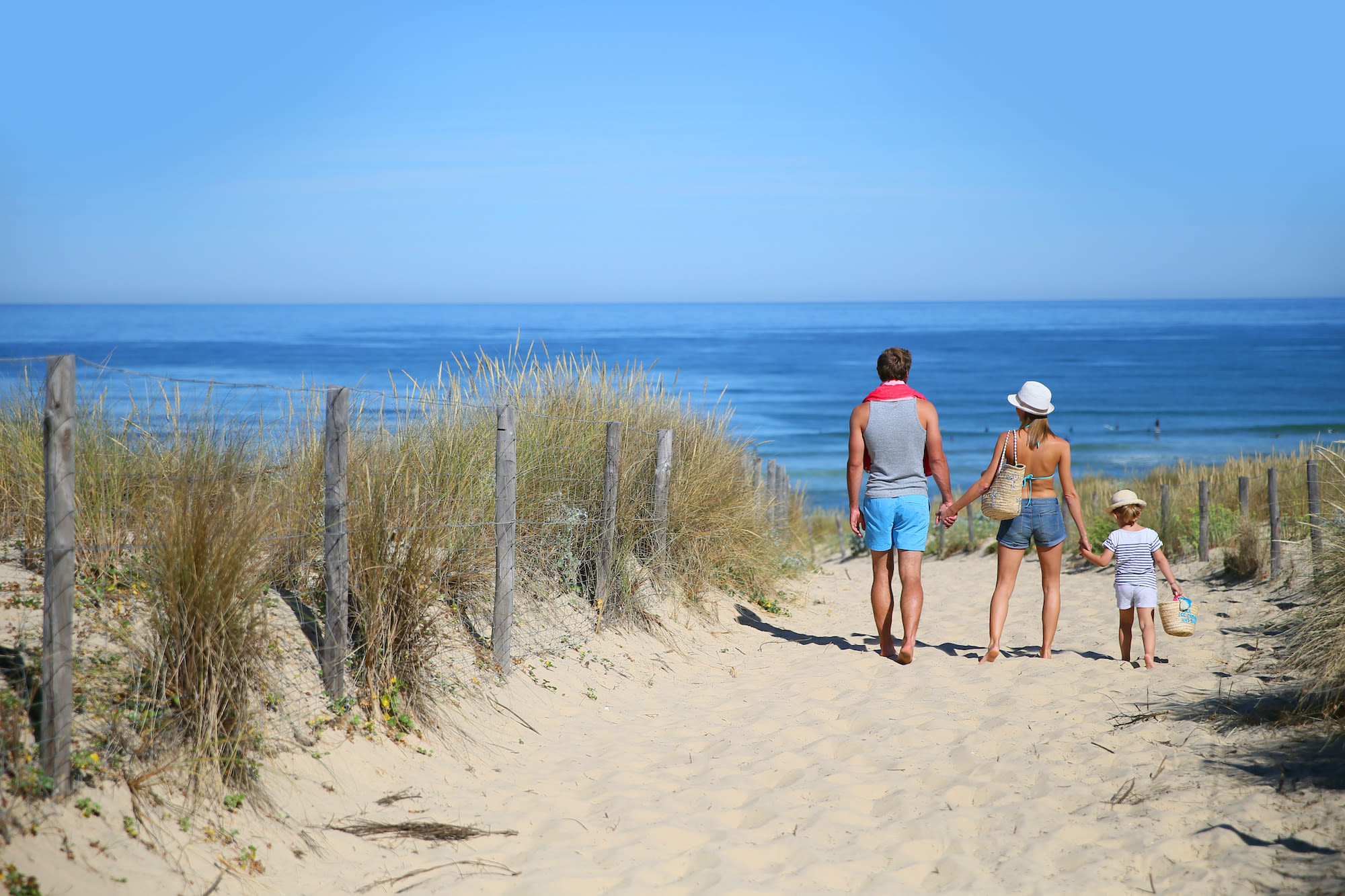 Familie van drie loopt door de duinen naar het strand