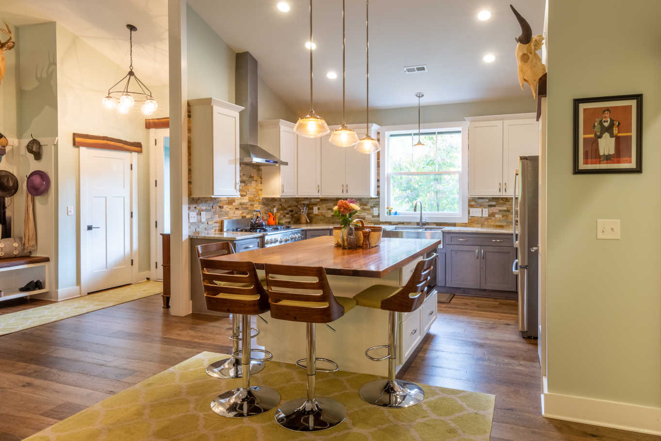 Dark wood floors, extra tall ceilings, and custom trim made from recycled barn wood elevate the kitchen of this Dog Series plan.