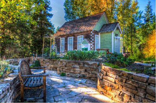 A charming cottage overlooks a garden and stone patio.