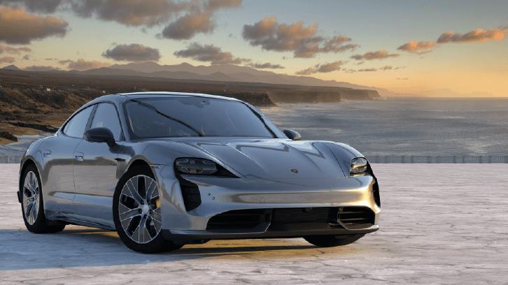 Srebrne Porsche Taycan zaparkowane nad morzem o zachodzie słońca. Srebrne Porsche Taycan zaparkowane nad morzem o zachodzie słońca.