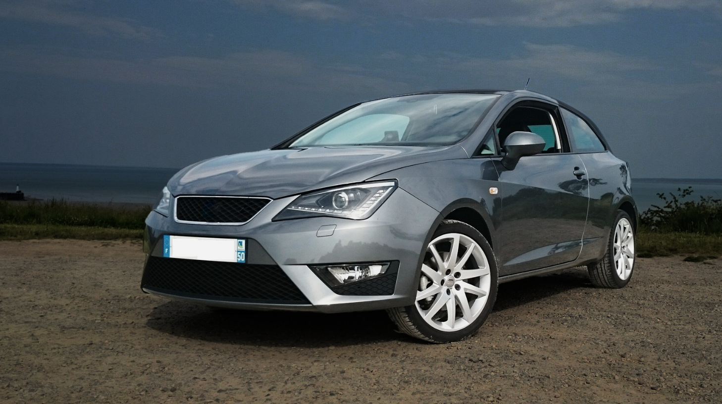 Coche SEAT plateado junto al mar.