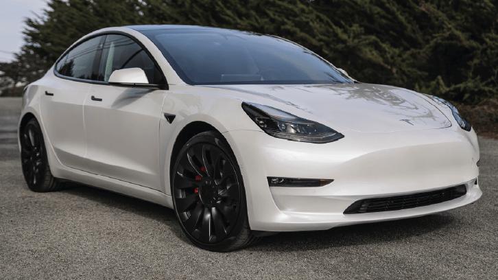 Biała Tesla Model 3 zaparkowana na zewnątrz w pochmurny dzień. Biała Tesla Model 3 zaparkowana na zewnątrz w pochmurny dzień.