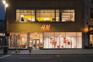 An exterior photo of the H&M storefront at 1505 Woodward at night.