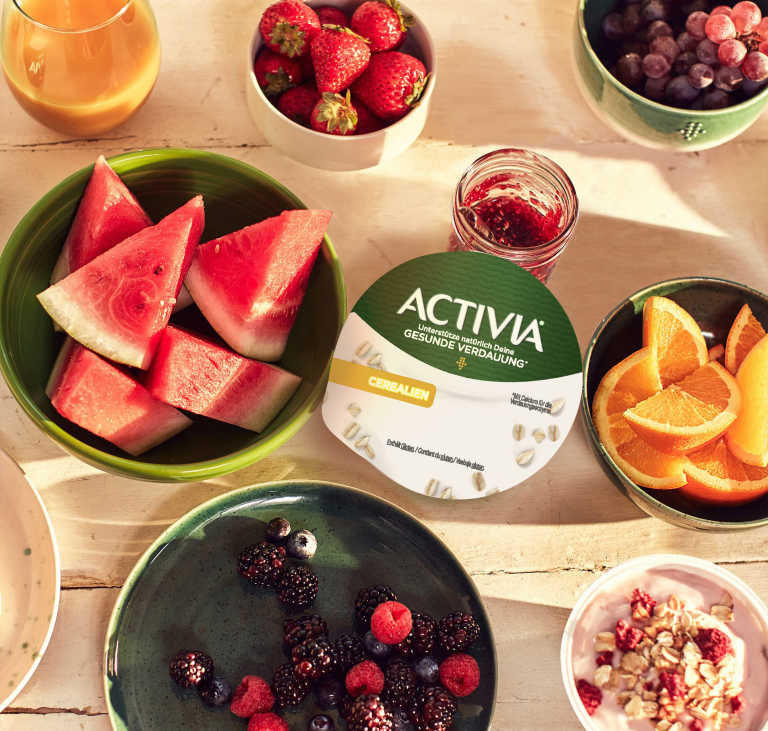 Activia Joghurt auf einem Tisch mit Obst 